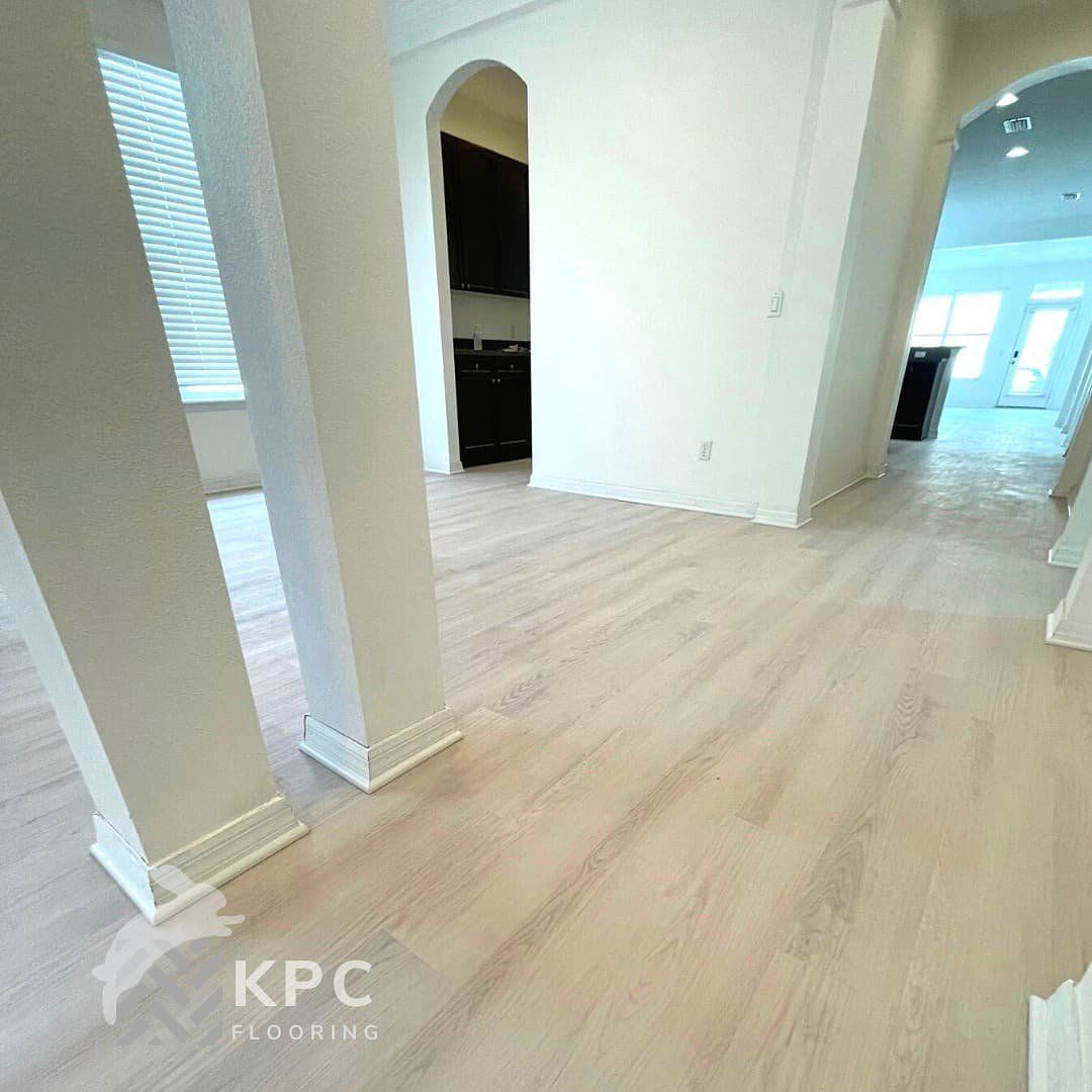 Light oak-look vinyl plank floor installed through an open hallway with columns and archways